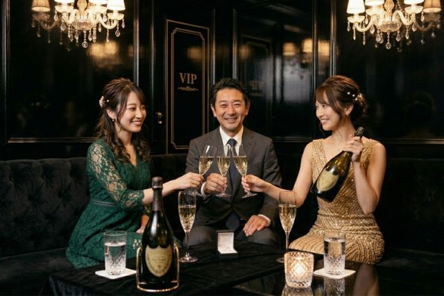 男性客を挟んで接客する二人のキャバ嬢