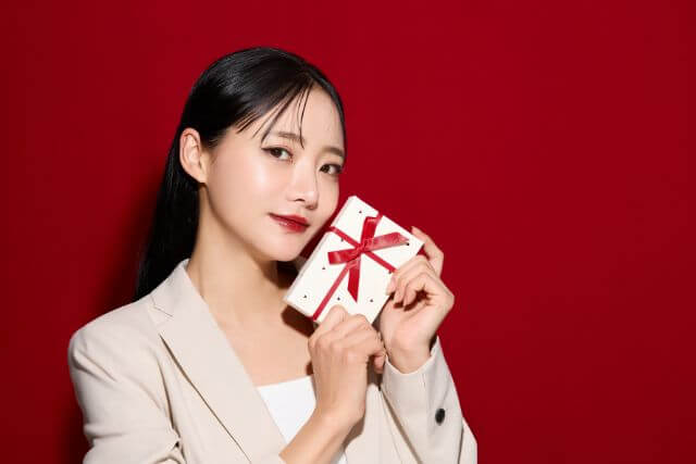 プレゼントボックスを顔の近くに持つ若い女性