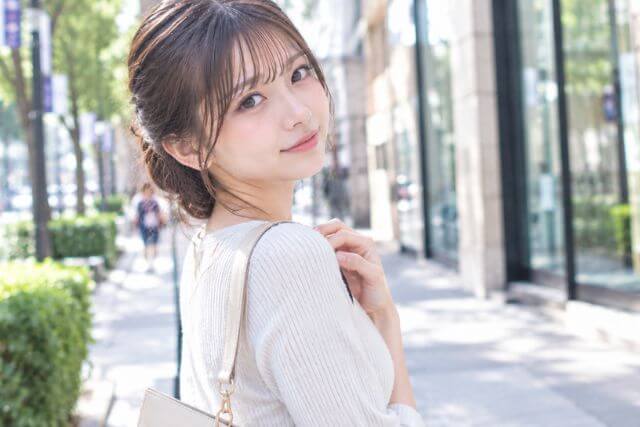 昼の街を歩く白い服の女性
