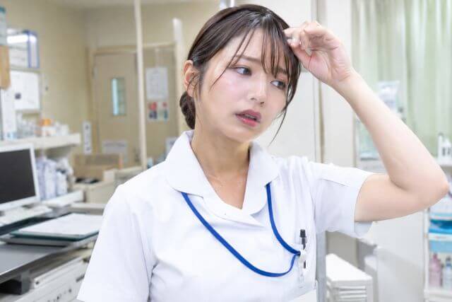 頭に手を当てる女性看護師