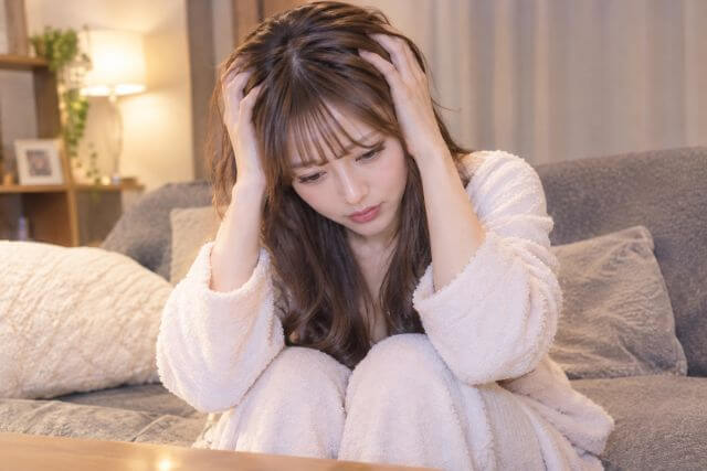 頭を抱える部屋着の女性