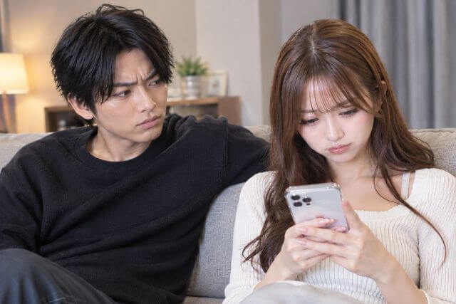 スマホを見る女性と不機嫌そうな男性