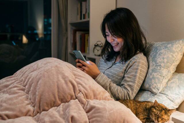 ベッドでスマホを触る女性