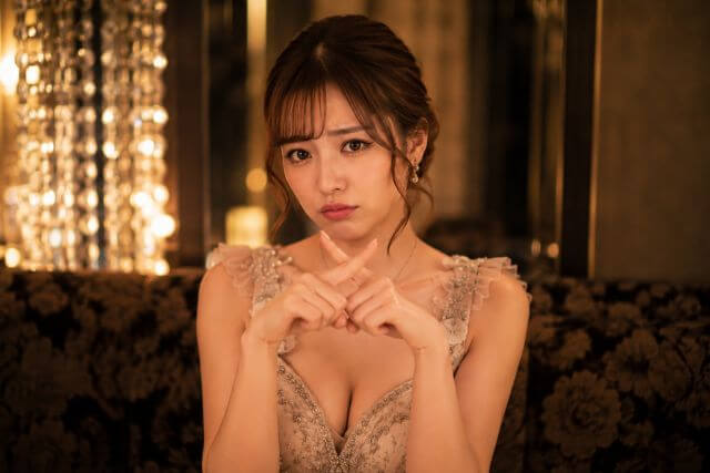 指でバツを作るドレスの女性