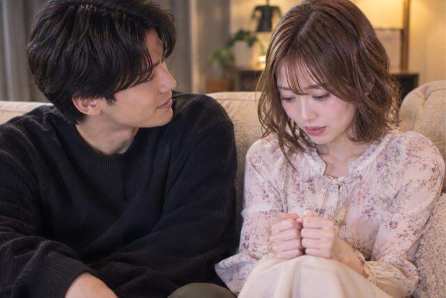 ソファに座る男女。緊張した様子の女性と笑顔の男性