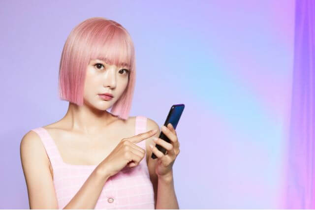 スマホを触るピンクの髪の女性