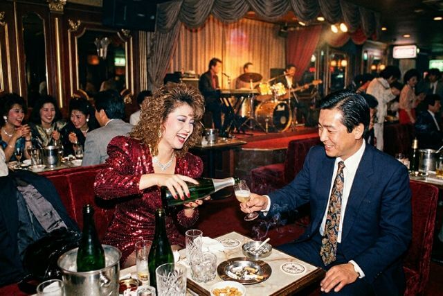 バブル期のキャバクラで女性が男性にお酌している様子