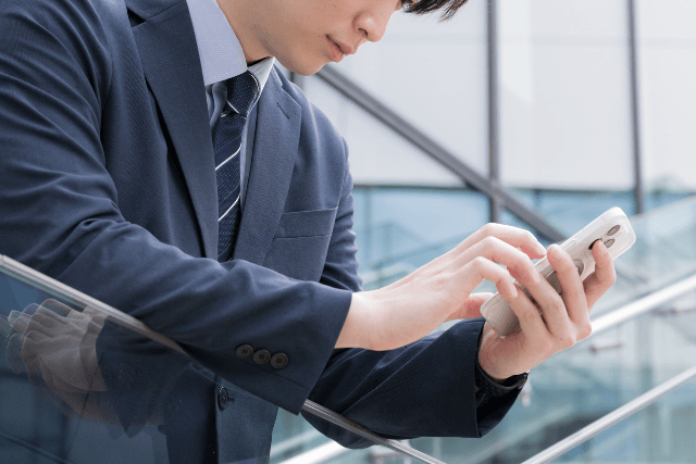 スーツの男性がスマホを触っている