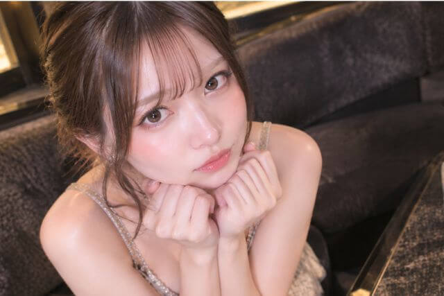 顎に両手を当てる上目使いの女性