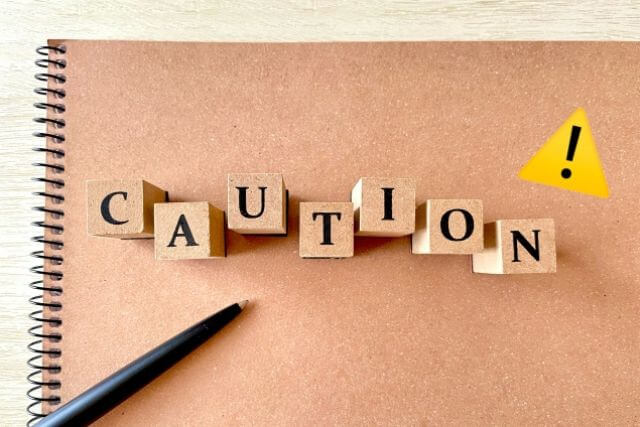 スケッチブックの上にCAUTIONと書かれた木のブロック