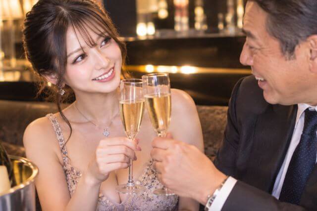 シャンパンで乾杯しているドレスの女性とスーツの50代の男性。