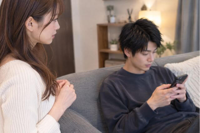 ソファでスマホを触っている男性。手前に立っている女性