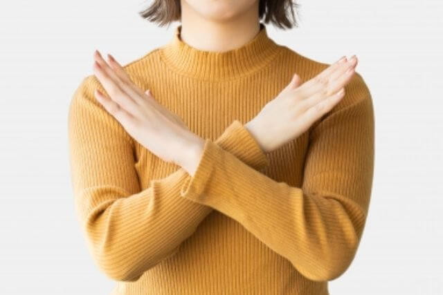 胸の前で腕をクロスしてバツ印を作る女性
