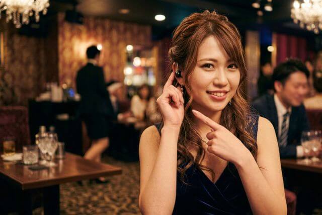 インカムに手を当てて笑顔のキャバ嬢