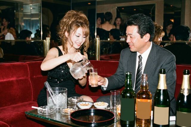 平成っぽいキャバクラで女性が男性にお酌している様子