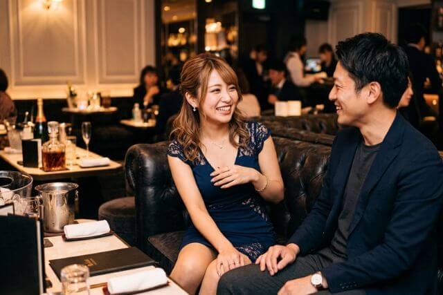 紺色のドレスのキャバ嬢と男性客が笑顔で話している様子
