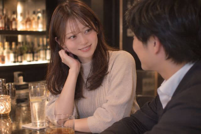 バーで男性と会話するロングヘアの女性