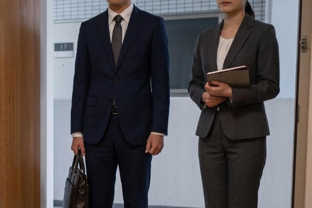 スーツを着た男女が立っている