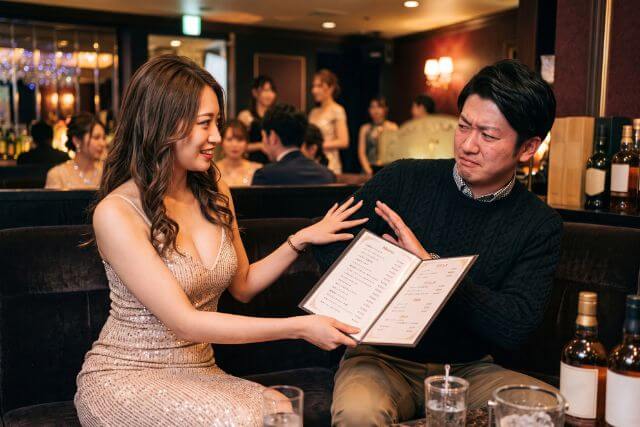 メニューを無理やりむせようとするドレスの女性と嫌がる男性