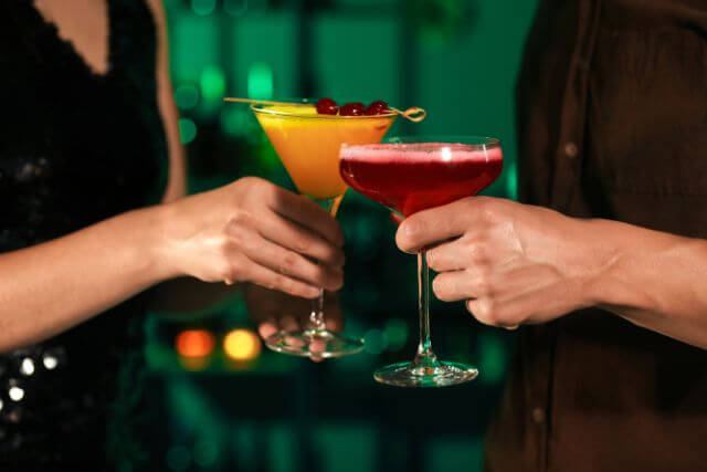 カクテルを持って乾杯する男女の手元