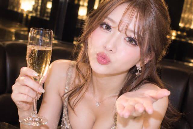 シャンパングラスを持って反対の手で投げキスする女性