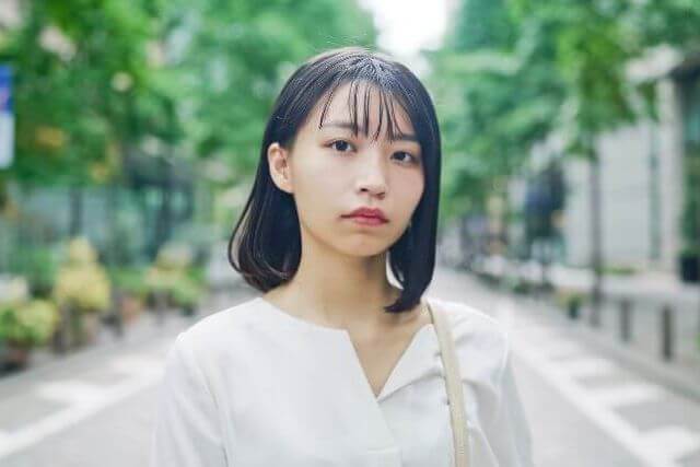 道路の真ん中に立つ白いシャツの女性