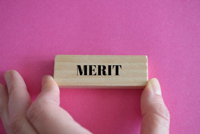 meritと書かれた木のブロックを持つ人の手