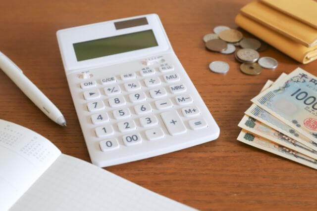電卓と紙幣・貨幣・ノートがテーブルに載っている