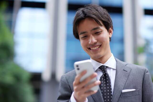 スマホを持って笑顔のスーツの男性