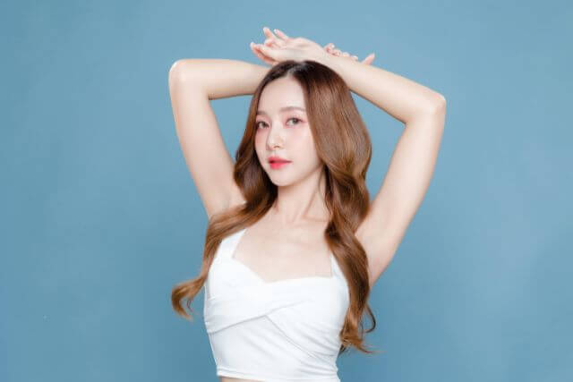頭の上に手を置いてポーズを取るロングヘアの女性