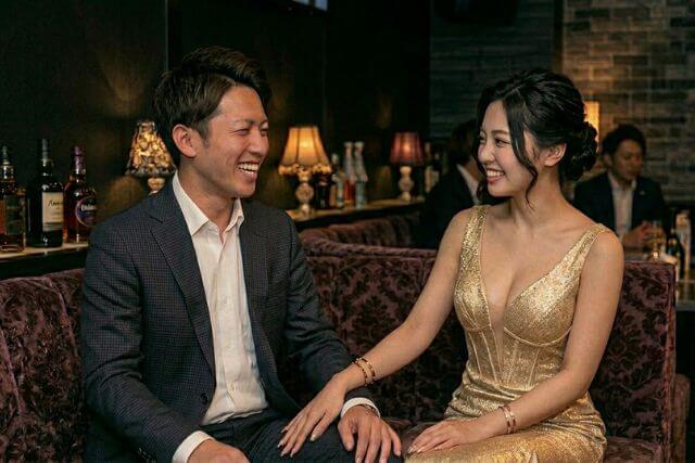男性客の太ももに手を乗せて談笑するゴールドのドレスのキャバ嬢