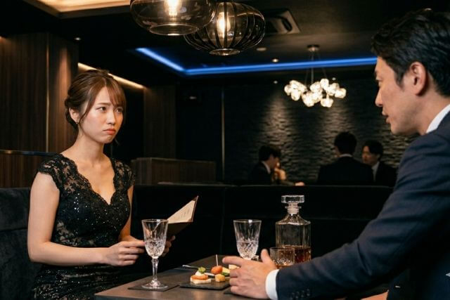 男性客を接客している困った顔のキャバ嬢
