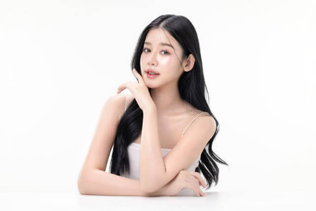 黒髪ロングでテーブルに手をついて座る若い女性