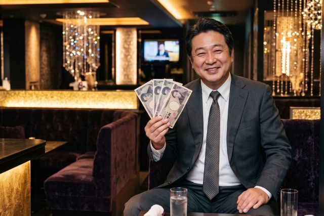 右手に8,000円分のお札を持つスーツの男性