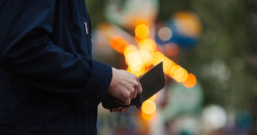 夕方の屋外で財布を開く男性の手元