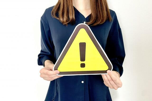 注意マークの看板を持つ女性