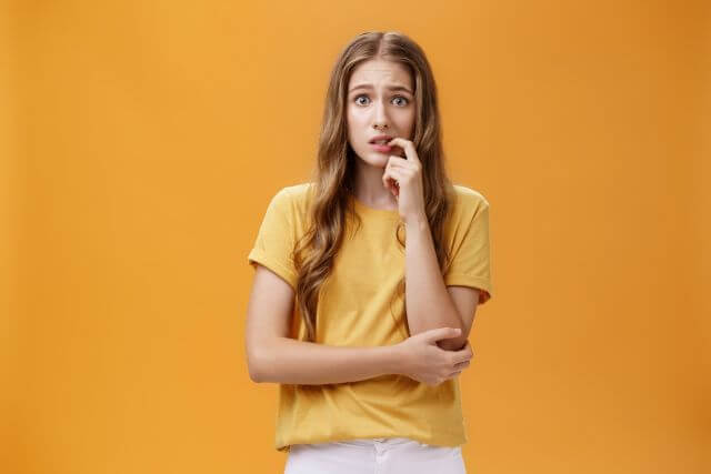 口に手をあて何かに悩む女性