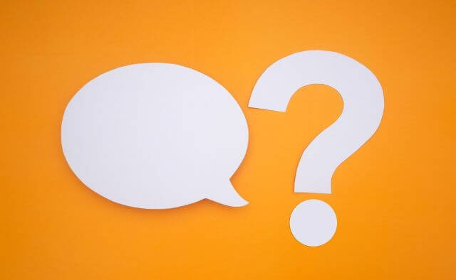 オレンジの背景の前にあるふきだしとハテナマーク