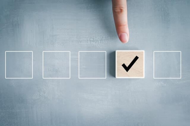 四角の中に置かれたチェックマークを指さす女性の手