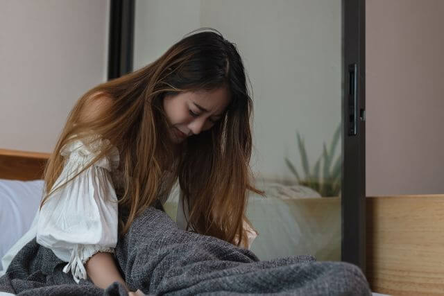 ベッドの上で泣く女性