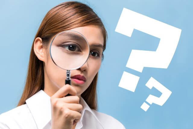 虫眼鏡でハテナマークを見る女性