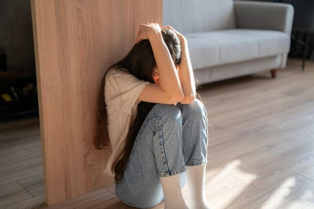 壁にもたれて頭を抱える女性