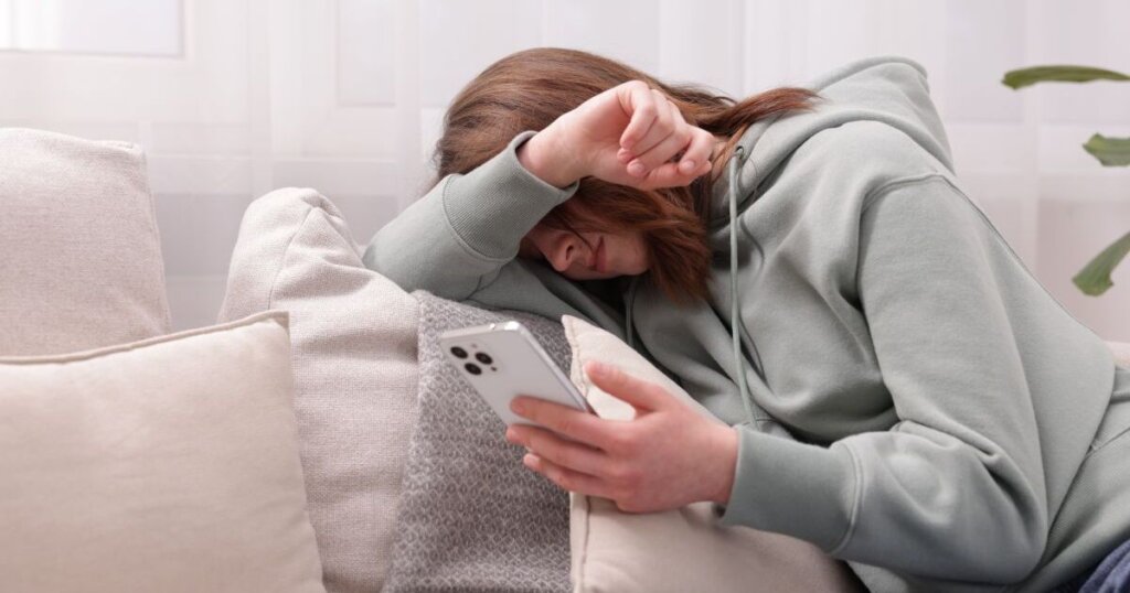 携帯を持ちながらうなだれる女性