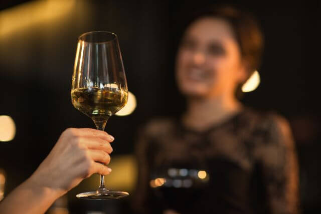 シャンパンを持ちながら笑顔で話す女性