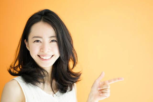 右側を指さして笑う若い女性