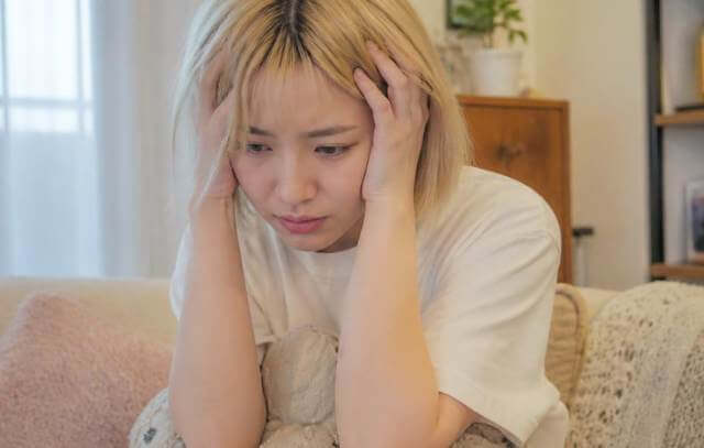 頭を抱えて悩んでいる様子の金髪女性