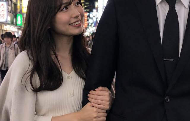 嬉しそうにスーツ姿の男性に腕を絡める若い日本人女性