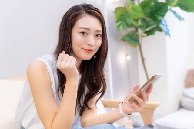 携帯を持ちながらガッツポーズする女性