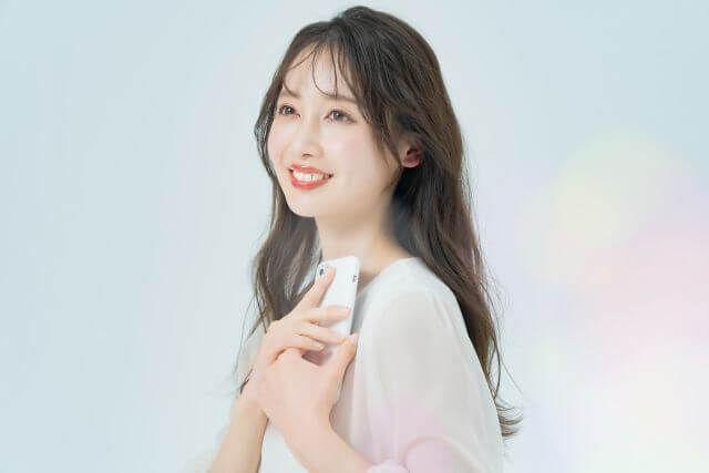 携帯を胸にあてる女性