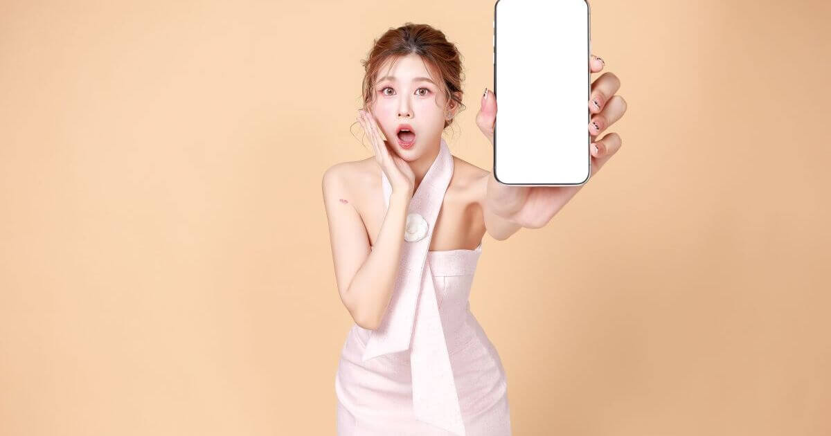 携帯の画面をこちらに向けているドレスの女性